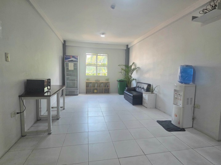 A dormitory common area with a fridge, a water dispenser and a sofa