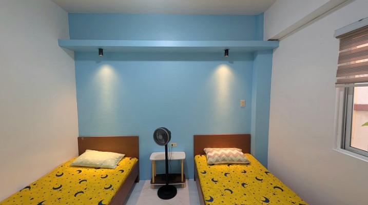 A twin dormitory room with sky-blue walls and yellow bedding