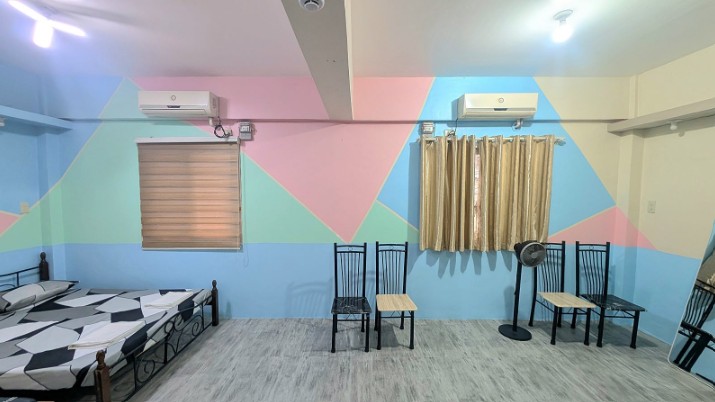 A spacious dormitory room with pink, sky-blue and mint patterned walls