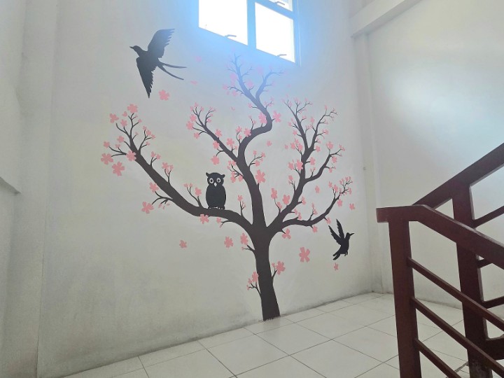 A dormitory stairwell wall painted with a cherry-blossom tree and birds