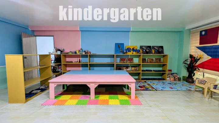 A kindergarten classroom with shelves of learning materials, a pink table and play mats