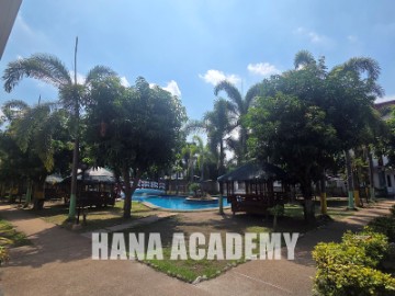 The HANA Academy pool surrounded by palm trees and gazebos