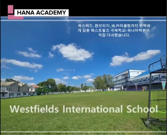 Lapangan olahraga hijau dan gedung sekolah Westfields International School di bawah langit biru