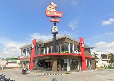 Gerai Jollibee dengan papan drive-thru 24 jam
