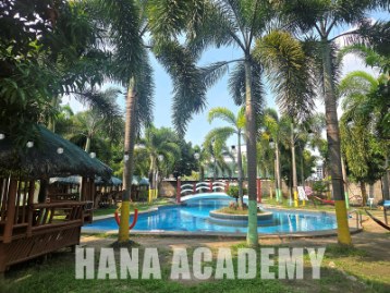 Kolam renang HANA Academy yang dikelilingi pohon palem dan gazebo