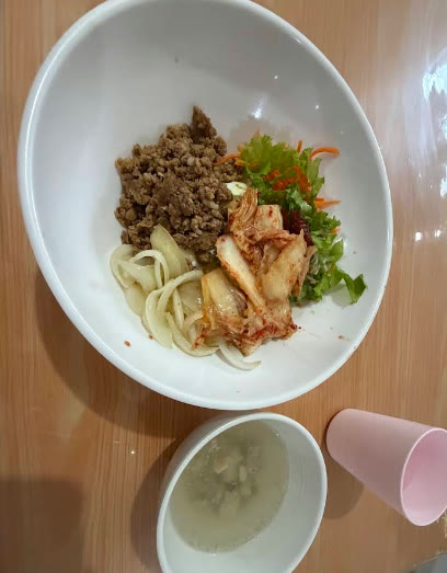 Semangkuk mi dengan daging cincang, kimchi, dan sayuran, disertai sup