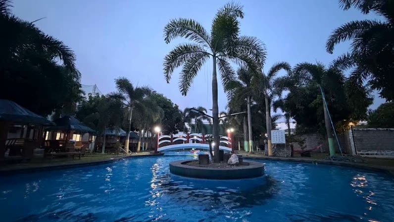 Kolam renang HANA Academy dan pohon palem saat senja