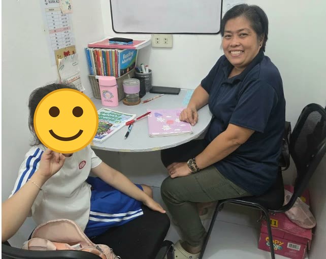 Seorang anak berpose tanda damai bersama gurunya di ruang kelas 1:1