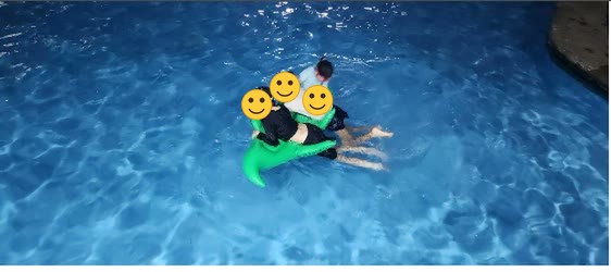 Anak-anak bermain di atas pelampung di kolam renang pada malam hari