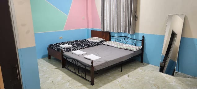 Dua tempat tidur dan cermin seluruh badan di kamar asrama berdinding warna pastel