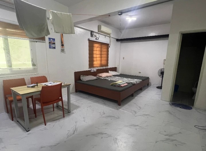 A family room with a dining table, beds and the bathroom door
