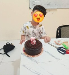 数字の5のろうそくが立ったチョコレートケーキの前の子ども