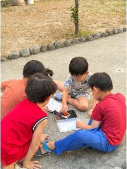 床に輪になって座り、一緒に絵を描く子どもたち