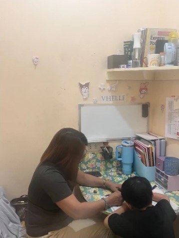 1:1教室で先生と向かい合って勉強する子どもの後ろ姿