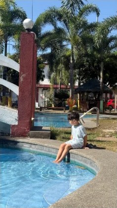 プールの縁に座って水に足をつける子ども