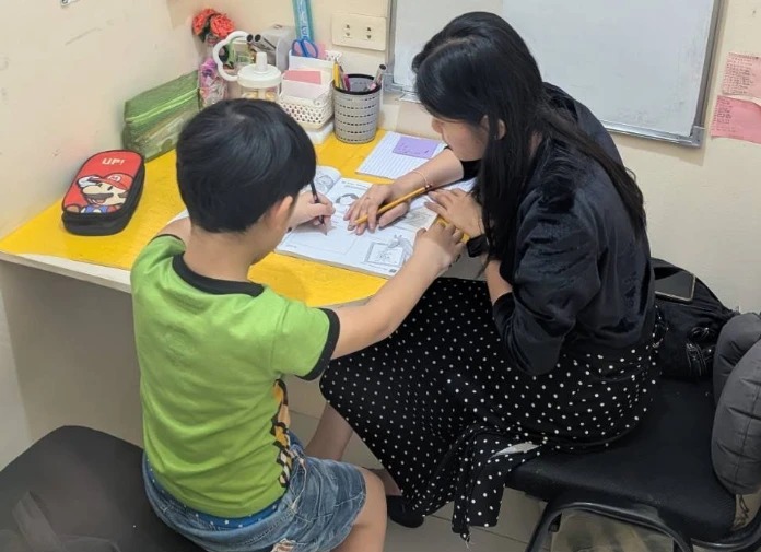 A child writing in a workbook with a teacher in a one-on-one class