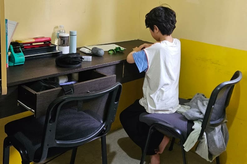 Seorang anak terlihat dari belakang, belajar di meja asrama