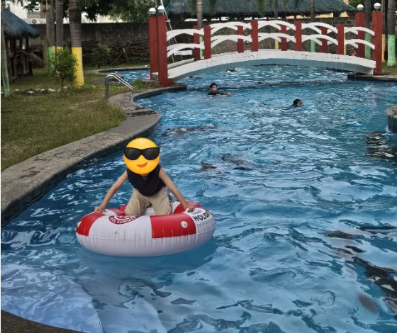 Seorang anak mengapung dengan ban renang di kolam akademi
